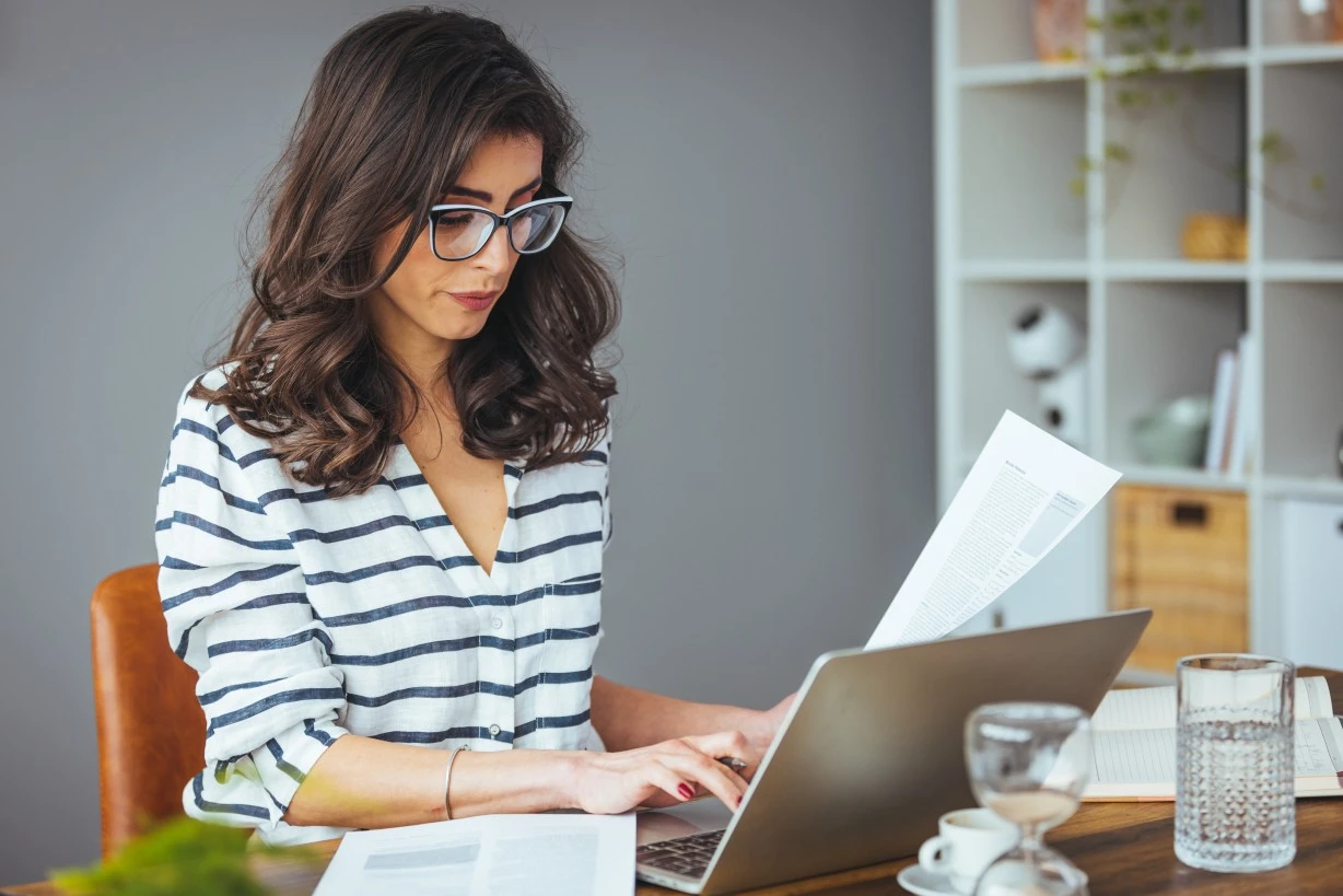 Professional woman sitting at desk using laptop to make an NDIS referral